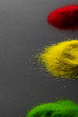 Photo for Vertical image of green, yellow and red powders with copy space on black background. Black history month, africa, black culture and history concept. - Royalty Free Image