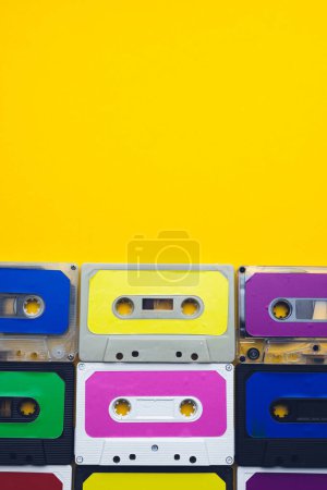 Photo for Overhead view of nine colourful cassette tapes with copy space on yellow background. Music, sound, listening, entertainment and nostalgia concept. - Royalty Free Image