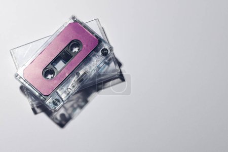 Photo for Overhead view of purple cassette tape and white box with copy space on white background. Music, sound, listening, entertainment and nostalgia concept. - Royalty Free Image