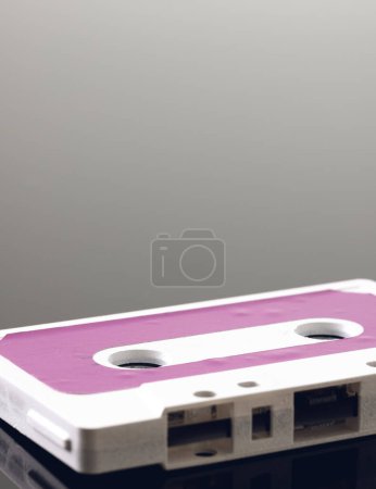 Photo for Close up of white and pink cassette tape with copy space on grey background with reflection. Music, sound, listening, entertainment and nostalgia concept. - Royalty Free Image