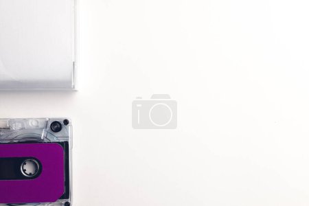 Photo for Overhead view of purple cassette tape and white box with copy space arranged on white background. Music, sound, listening, entertainment and nostalgia concept. - Royalty Free Image