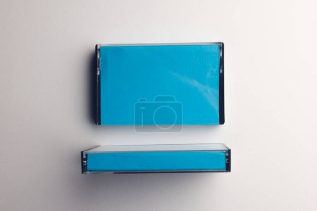 Foto de Vista aérea de dos cajas de cinta de casete azul dispuestas sobre fondo blanco. Música, sonido, escucha, entretenimiento y concepto de nostalgia. - Imagen libre de derechos
