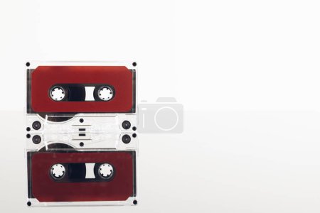 Téléchargez les photos : Gros plan de cassette rouge sur fond blanc avec réflexion. Concept de musique, son, écoute, divertissement et nostalgie. - en image libre de droit