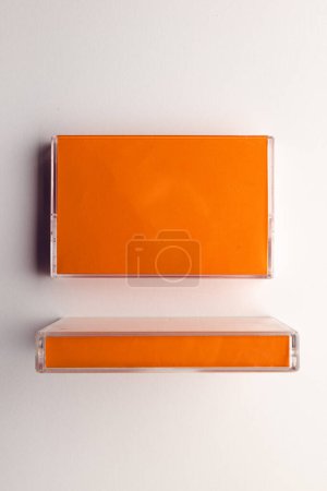 Téléchargez les photos : Vue aérienne de deux cassettes orange disposées sur fond blanc. Concept de musique, son, écoute, divertissement et nostalgie. - en image libre de droit