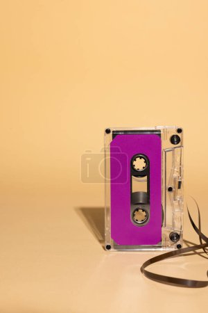 Photo for Close up of purple cassette tape with copy space on beige background. Music, sound, listening, entertainment and nostalgia concept. - Royalty Free Image