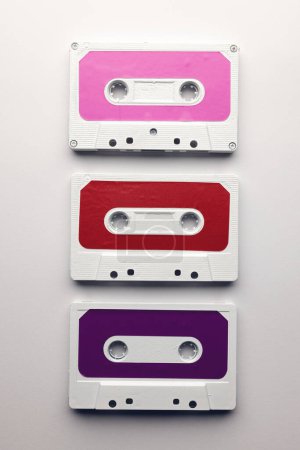 Téléchargez les photos : Vue aérienne de trois cassettes colorées disposées sur fond blanc. Concept de musique, son, écoute, divertissement et nostalgie. - en image libre de droit