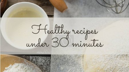Photo for Healthy recipes under 30 minutes text on white band over bowls of ingredients and dough on worktop. Food, cooking, recipes and healthy lifestyle, digitally generated image. - Royalty Free Image