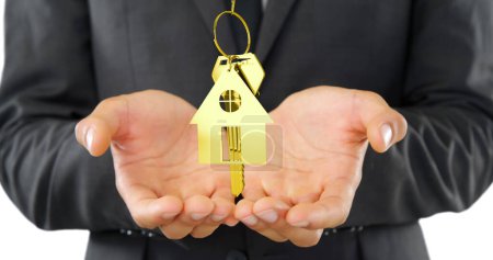 Foto de Un hombre de negocios presenta una llave dorada de la casa, que simboliza la inversión inmobiliaria. Su atuendo profesional sugiere un entorno empresarial formal, haciendo hincapié en la importancia de las transacciones inmobiliarias. - Imagen libre de derechos