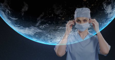 Téléchargez les photos : Portrait de chirurgienne portant un masque facial sur fond bleu. traitement médical et concept de technologie - en image libre de droit