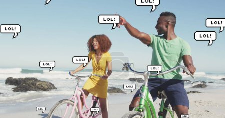 Photo for Image of speech bubbles with lol text over happy couple riding bikes on beach. digital interface, social media and global technology concept digitally generated image. - Royalty Free Image