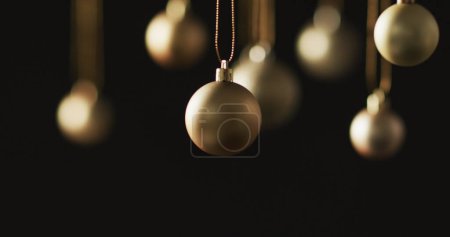 Photo for Happy holidays text with silver christmas baubles hanging on dark background. Christmas, decorations, tradition, greetings and celebration digitally generated image. - Royalty Free Image
