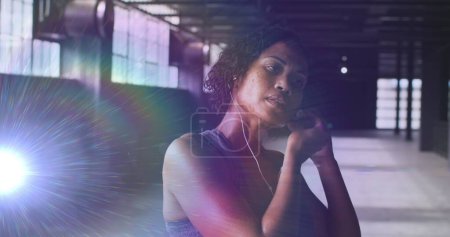 Photo for Image of glowing light over woman putting earphones on before workout in gym. Digital interface global sport and performance concept digitally generated image. - Royalty Free Image