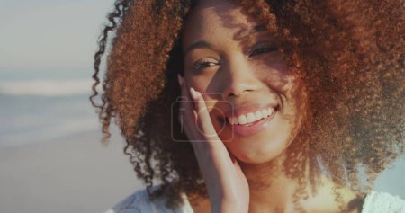 Foto de Joven mujer afroamericana sonríe brillantemente al aire libre, con espacio para copias. Su expresión alegre captura la esencia de un día de verano despreocupado en la playa. - Imagen libre de derechos