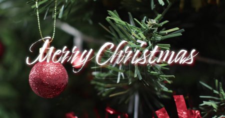 Téléchargez les photos : Joyeux Noël texte en blanc sur boule rouge sur l'arbre de Noël. Noël, tradition, salutations et célébration image générée numériquement. - en image libre de droit