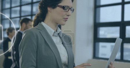 Photo for Caucasian woman reviews a document in an office. She's focused on her task, exemplifying professionalism in a corporate environment. - Royalty Free Image