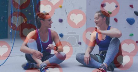 Photo for Multiple heart icons floating against two caucasian fit women fist bumping at the gym. sports, fitness and social media networking technology concept - Royalty Free Image