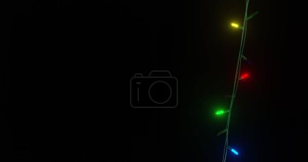 Téléchargez les photos : Strand de lumières de Noël colorées clignotant sur fond noir, espace de copie. Noël, décorations, tradition et célébration image générée numériquement. - en image libre de droit