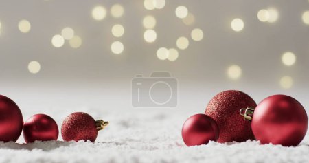 Photo for Red Christmas ornaments rest on snowy surface, with copy space. Festive decorations evoke the holiday spirit and winter season charm. - Royalty Free Image