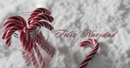Photo for Feliz navidad text with christmas candy canes on snow background. Christmas, tradition, spanish, greetings and celebration digitally generated image. - Royalty Free Image