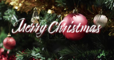Foto de Feliz navidad texto sobre decoraciones colgando en el árbol de navidad. Navidad, tradición, saludos y celebración imagen generada digitalmente. - Imagen libre de derechos