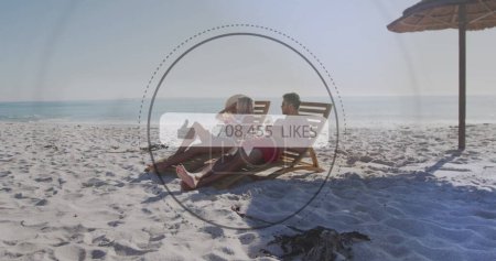 Foto de Imagen de la burbuja del habla con gustos de texto y números sobre la pareja en tumbonas en la playa. interfaz digital, redes sociales y concepto de tecnología global imagen generada digitalmente. - Imagen libre de derechos