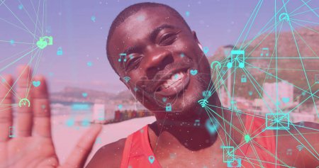 Foto de Globos de iconos digitales girando contra el hombre afroamericano en forma saludando mirando a la cámara. concepto de deportes, fitness y tecnología - Imagen libre de derechos