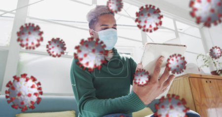 Photo for Image of floating covid-19 cells with woman using digital tablet in office wearing face masks. Healthcare and protection during coronavirus covid 19 pandemic, digitally generated image - Royalty Free Image