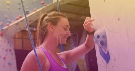 Kaukasisch fitte Frau mit Seil im Begriff, eine Wand im Fitnessstudio zu erklimmen. Sport-, Fitness- und Technologiekonzept