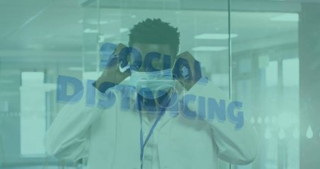 Photo for Image of words social distancing with scientist putting face mask on. Healthcare and protection during coronavirus covid 19 pandemic, digitally generated image - Royalty Free Image