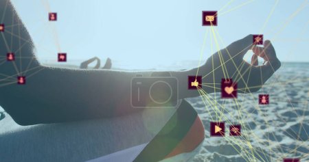 Photo for Globes of digital icons spinning against mid section of a person meditating at the beach. healthy living and technology concept - Royalty Free Image