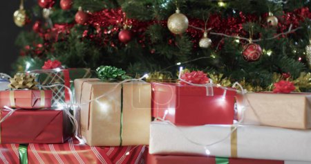 Téléchargez les photos : Cadeaux enveloppés assis sous un arbre de Noël festif à la maison. La scène capture l'esprit de donner et de célébrer les fêtes en famille. - en image libre de droit