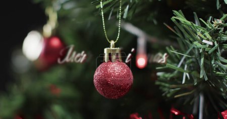 Téléchargez les photos : Un ornement de Noël rouge est suspendu à un arbre de fête. Les décorations de vacances créent une atmosphère chaleureuse et festive à la maison. - en image libre de droit