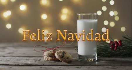 Photo for Feliz navidad text in orange over christmas cookies and milk and bokeh lights background. Christmas, tradition, greetings and celebration digitally generated image. - Royalty Free Image