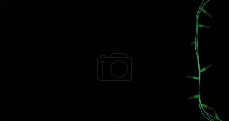 Foto de Strand of yellow christmas string lights flashing on black background, copy space. Navidad, decoraciones, tradición y celebración de imagen generada digitalmente. - Imagen libre de derechos
