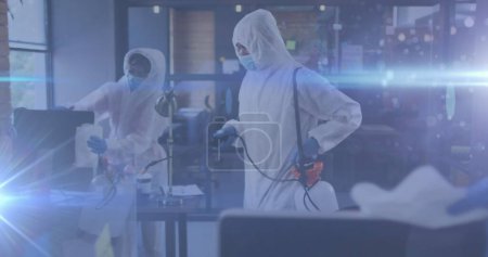 Photo for Image of glowing light trails over people disinfecting office with spray. global covid 19 pandemic, health and medicine concept digitally generated image. - Royalty Free Image