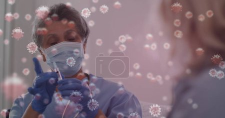 Foto de Imagen de 19 células covid sobre enfermeras que preparan la vacunación usando mascarilla facial. mundial covid 19 pandemia, salud y medicina concepto de imagen generada digitalmente. - Imagen libre de derechos