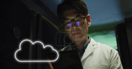 Foto de Imagen de la nube sobre el hombre asiático trabajando en la sala de servidores. red, programación, ordenadores y tecnología concepto de imagen generada digitalmente. - Imagen libre de derechos