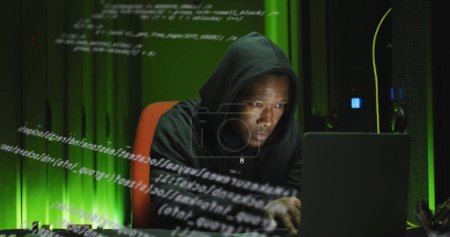 Téléchargez les photos : Image de traitement de données sur un homme afro-américain travaillant sur un ordinateur portable dans une salle de serveurs. réseau, programmation, informatique et concept technologique - en image libre de droit