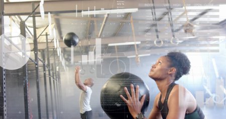 Photo for Image of data on interface over african american woman cross training with medicine ball at gym. Fitness, exercise, strength, data, digital interface and technology digitally generated image. - Royalty Free Image