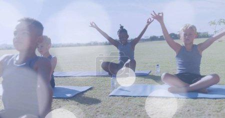 Téléchargez les photos : Image de taches de lumière blanche sur des écoliers heureux et diversifiés faisant du yoga en classe en plein air. Santé, bien-être, école, éducation, enfance et apprentissage, image numérique. - en image libre de droit
