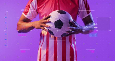 Foto de Hombre afroamericano sostiene una pelota de fútbol, con espacio para copiar. Studio shot con un vibrante fondo púrpura enfatiza el tema deportivo. - Imagen libre de derechos