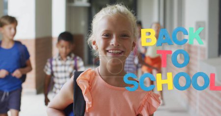 Téléchargez les photos : Image de texte coloré de retour à l'école sur une écolière caucasienne souriante dans le couloir de l'école. École, éducation, enfance et apprentissage, image générée numériquement. - en image libre de droit