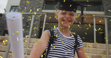 Photo for Image of gold confetti over happy caucasian schoolgirl with diploma and mortar board. Achievement, graduation, school, education, childhood and learning, digitally generated image. - Royalty Free Image