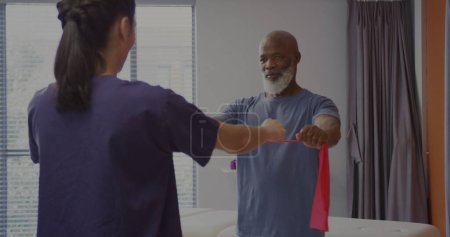 Ein älterer afroamerikanischer Mann übt mit einem Therapeuten in einem Reha-Zentrum. 