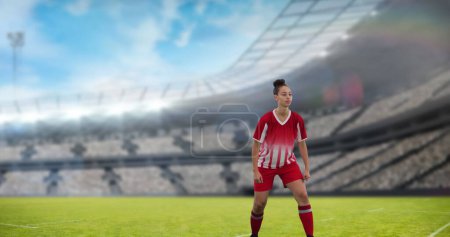 Image of biracial female soccer player over stadium. Global sport, patriotism and digital interface concept digitally generated image.