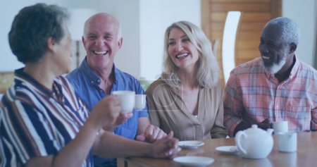 Photo for Diverse group of friends share laughter over coffee at home. Their joyful interaction highlights the warmth of close companionship in a cozy setting. - Royalty Free Image