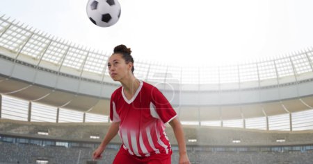 Bild einer zweirassigen Fußballerin über dem Stadion. Globaler Sport, Patriotismus und digitales Schnittstellenkonzept digital generiertes Image.