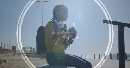 Téléchargez les photos : Image d'icônes technologiques sur une femme mangeant un sandwich sur une promenade au bord de la mer. Interface numérique concept mondial de sport et de performance image générée numériquement. - en image libre de droit