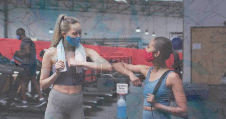 Téléchargez les photos : Réseau de connexions contre deux femmes se saluant en se touchant les coudes au gymnase. coronavirus covid-19 pandémie et concept de conditionnement physique - en image libre de droit