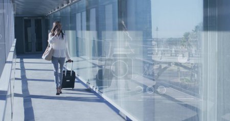Image of financial data processing over biracial businesswoman in airport. Global travel, business, finances, computing and data processing concept digitally generated image.